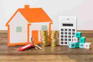 Free photo house, key, stacked coins, calculator and math blocks on wooden table