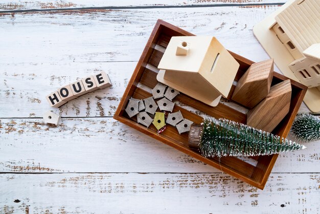 House model; bird houses and christmas tree in the wooden tray with text on white textured backdrop