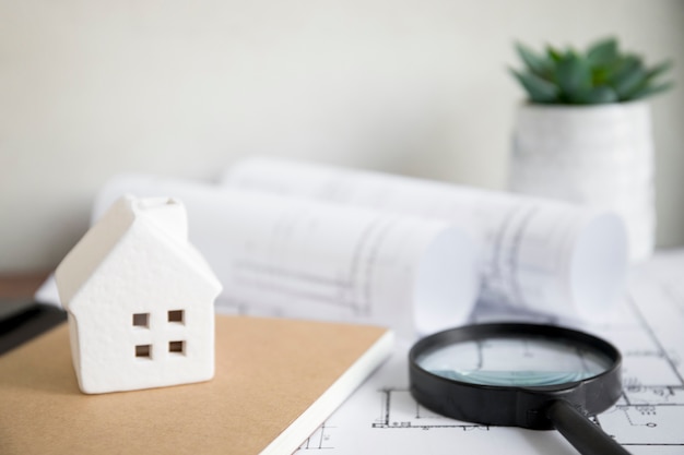 House and notebook near magnifying glass and drafts