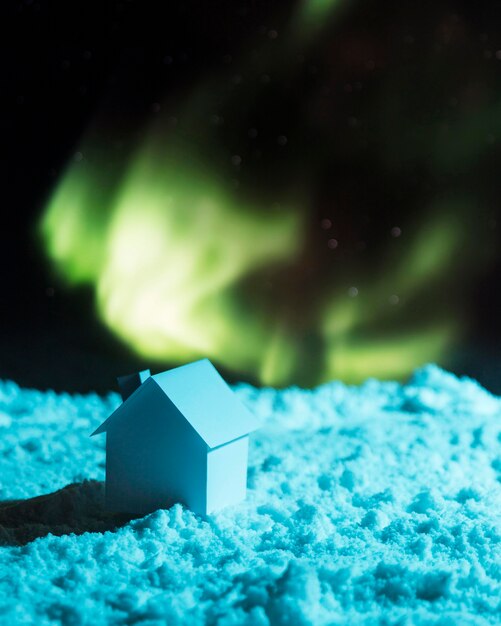 House on snow with aurora borealis