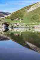 Foto gratuita una casa circondata da un bellissimo paesaggio e il suo riflesso sul lago enol in spagna