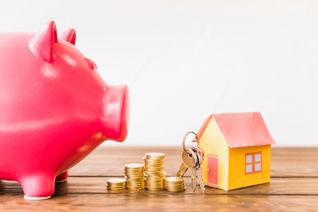 Free photo house with key and stacked coins besides piggybank