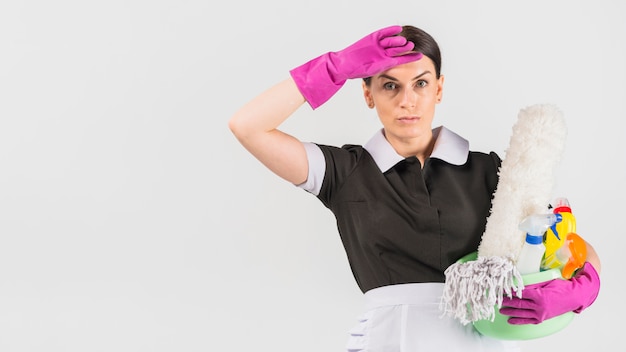 Housekeeper with detergents mopping brow