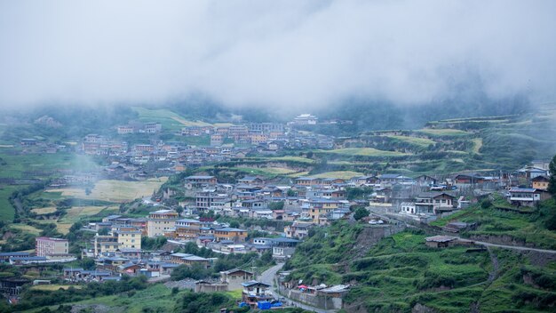Houses of a small town surrounded by forests and a foggy cloud
