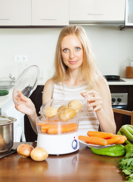 housewife cooking potatoes with electric steamer