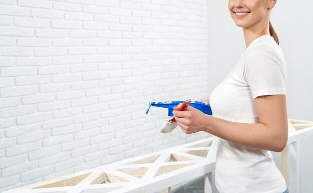 Housewife refreshing wooden shelves with white paint