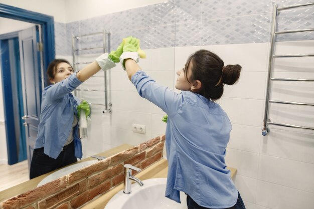 Housewife woking at home. Lady in a blue shirt. Woman in a bathroom.