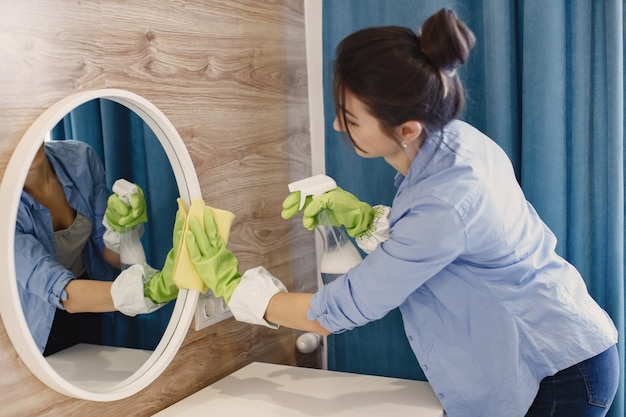 Housewife woking at home. lady in a blue shirt. woman clean mirror.