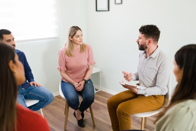 How are you feeling? Latin counselor asking questions about her mental health and depression to a caucasian young woman during a group therapy session