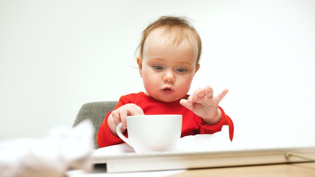 How tired i am. child baby girl sitting with keyboard of modern computer or laptop in white