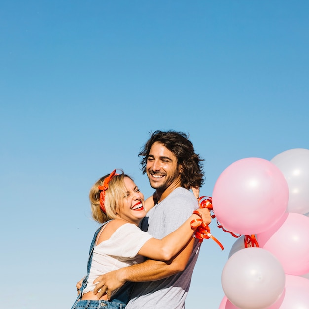 Бесплатное фото Обнимающая пара с воздушными шарами