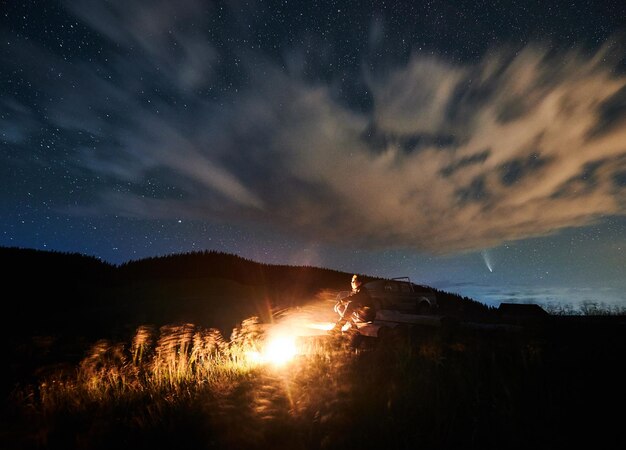 Human enjoying cozy bonfire and beautiful starry sky