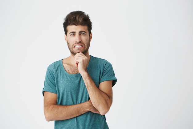 Human face expressions, emotions and feelings. Handsome young attractive man  with thoughtful and skeptical expression, crossing his arms, trying to remember something