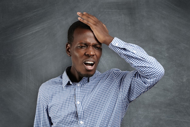 Human face expressions and emotions. forgetful dark-skinned man holding his hand on his head with a painstaking expression as he struggling to remember something.