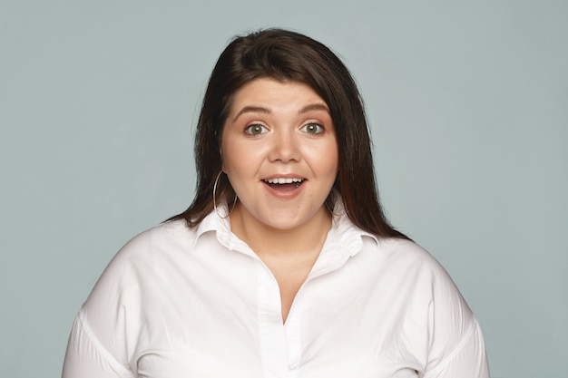 Free photo human facial exppressions and reaction. attractive emotional young businesswoman with curvy body posing with mouth wide opened, stunned with positive news, expressing great excitement