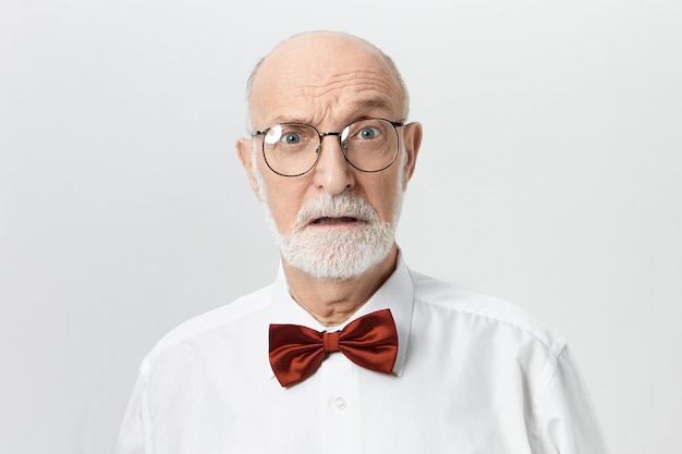 Human facial expressions, emotions, feelings and reaction.  attractive unshaven retired man in spectacles having shocked scared look. Bearded European male pensioner expressing fear