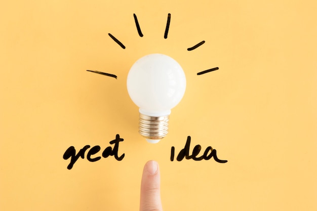 Free photo human finger pointing towards light bulb with great idea text