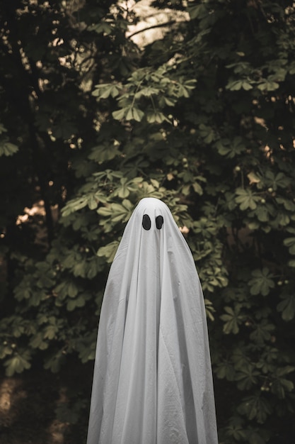 Foto gratuita umano in costume da fantasma in piedi vicino a bush