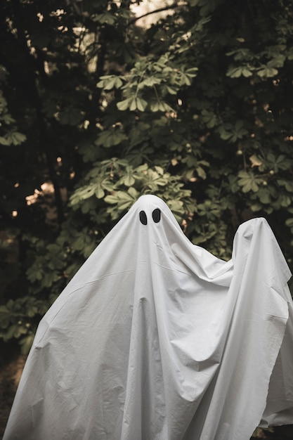Human in ghost costume with rising hands