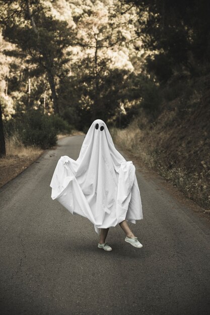 Human in ghost suit posing on countryside route