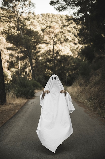 Human in ghost suit with visible hands on countryside route