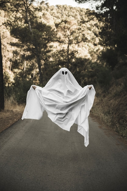 Human in gloomy ghost costume flying in countryside 