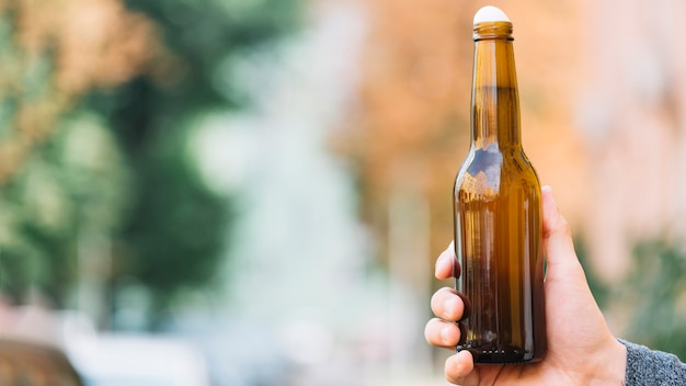 Human hand holding beer bottle