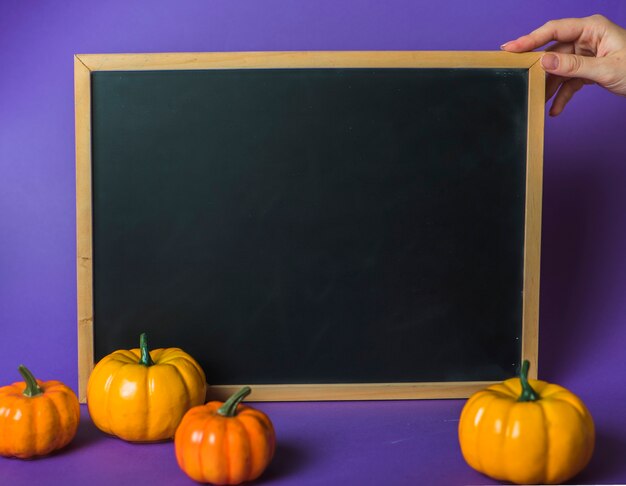 Human hand holding desk near pumpkins