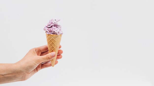 human hand holding ice cream in wafer cup