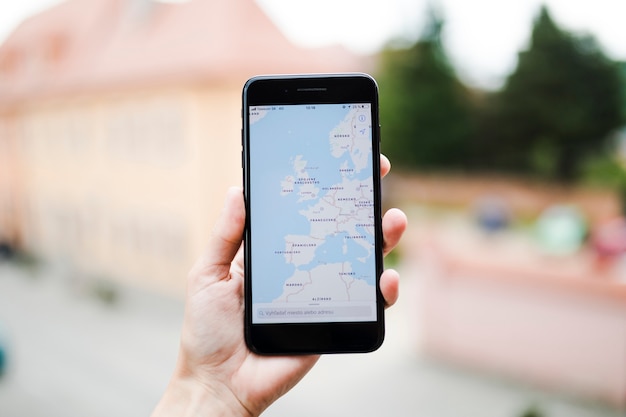 Foto gratuita mano umana che tiene il telefono cellulare con la navigazione gps mappa sullo schermo