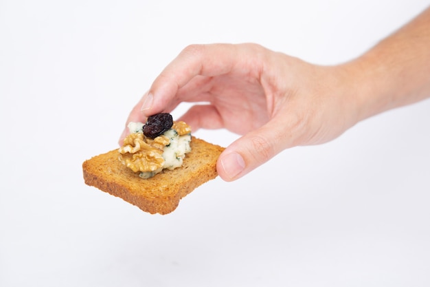 Human hand holding toasted slice of bread with blue cheese