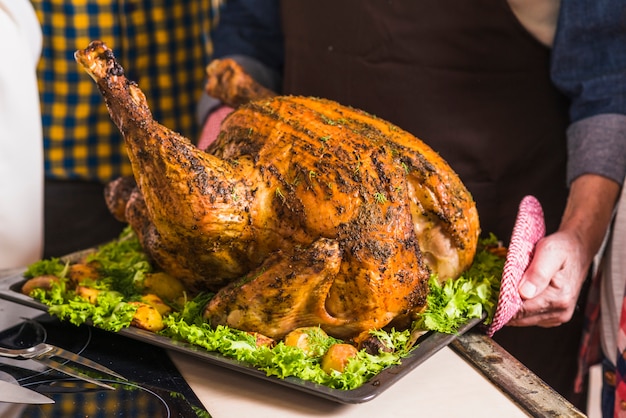 Human hand holding tray with roasted ham