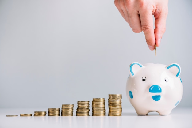 Human hand inserting coin in piggybank