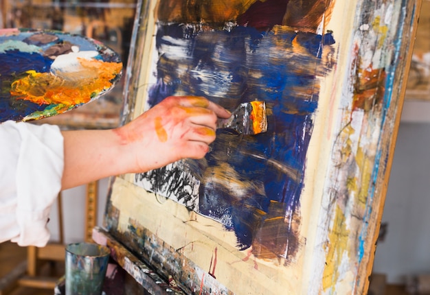 페인트 브러시와 캔버스에 인간의 손 그림