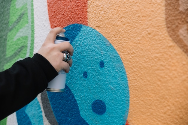 Graffiti della pittura della mano umana con la latta dell'aerosol