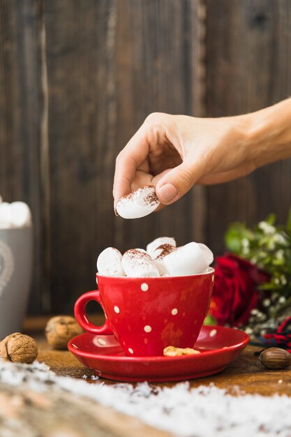 Human hand putting marshmallow in cup