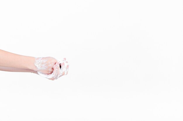 Human hand in soapsuds on white backdrop