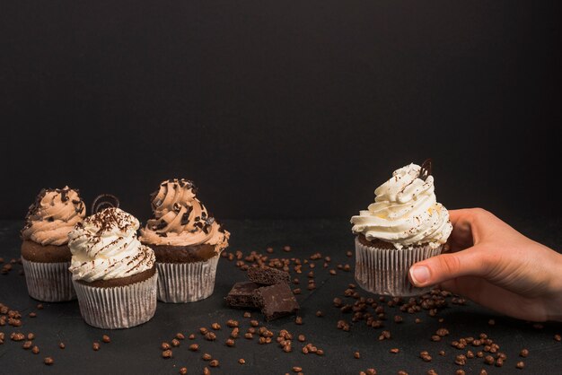 Human hand taking out muffin against black background