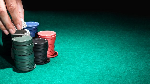 Human hand with casino chips on green table