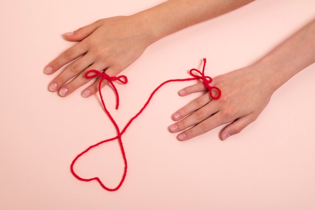 ハートの形の赤い糸で接続された人間の手