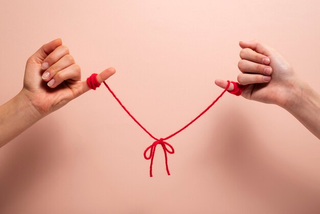 Human hands connected with red thread