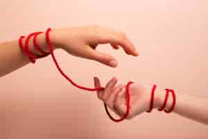 Free photo human hands connected with red thread