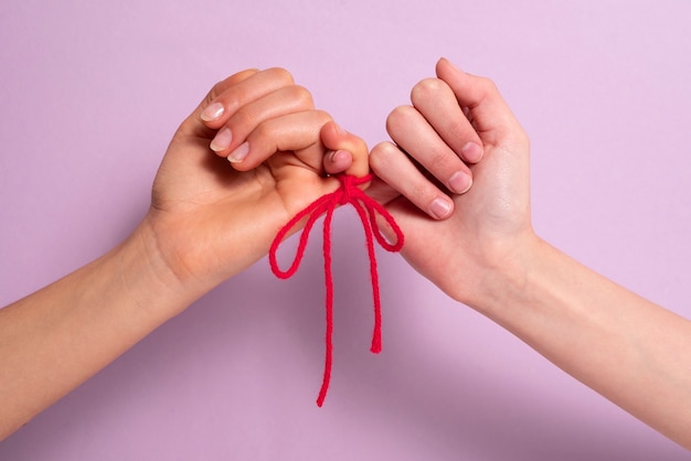 Human hands connected with red thread