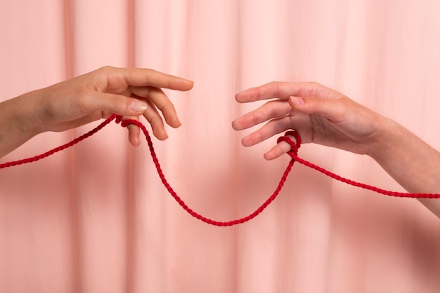 Human hands connected with red thread