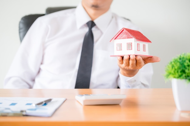 Human hands holding model of dream house.