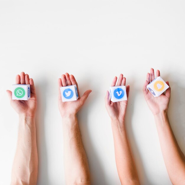 Human hands in a row holding boxes of various mobile application icons