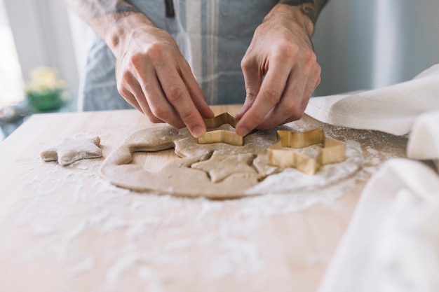 Human hands using cookie cutter on dough