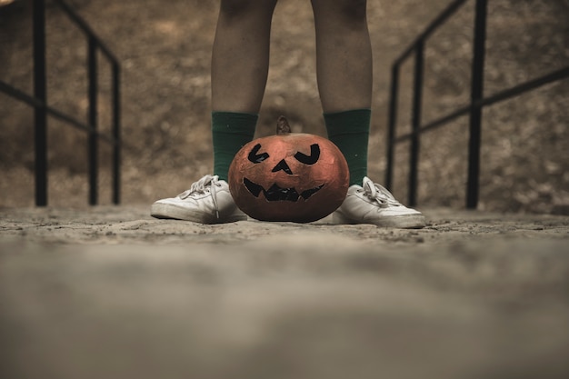 Foto gratuita gambe umane con la zucca di halloween posta sui passaggi pedonali nel parco