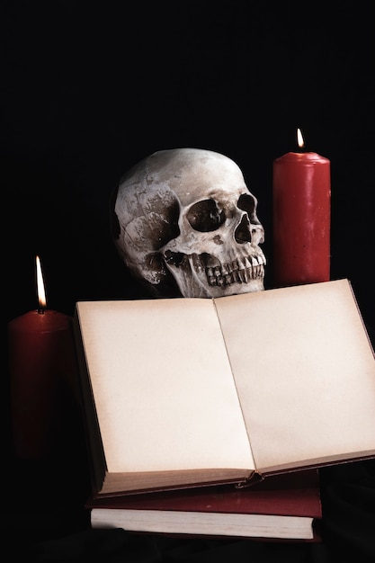 Free photo human skull with book mock-up and candles