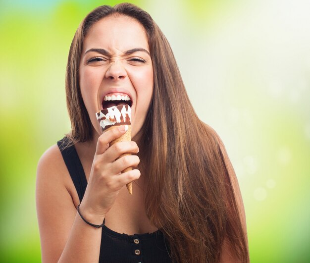 Hungry brunette girl biting chocolate ice cream.